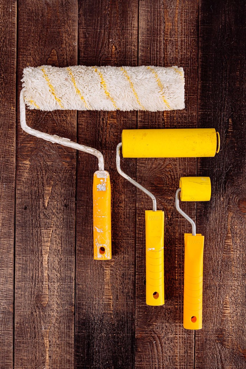 Free Top view of yellow paint rollers arranged on a wooden table for DIY projects. Stock Photo