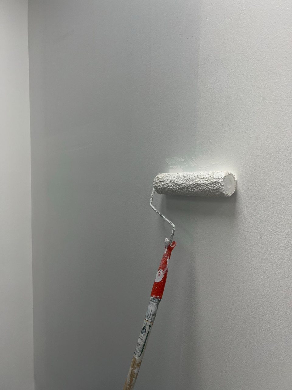 Free Smooth white paint applied on a wall using a roller, showcasing home renovation process. Stock Photo
